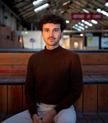 Producer William Board sitting on a stool in warehouse, headshot